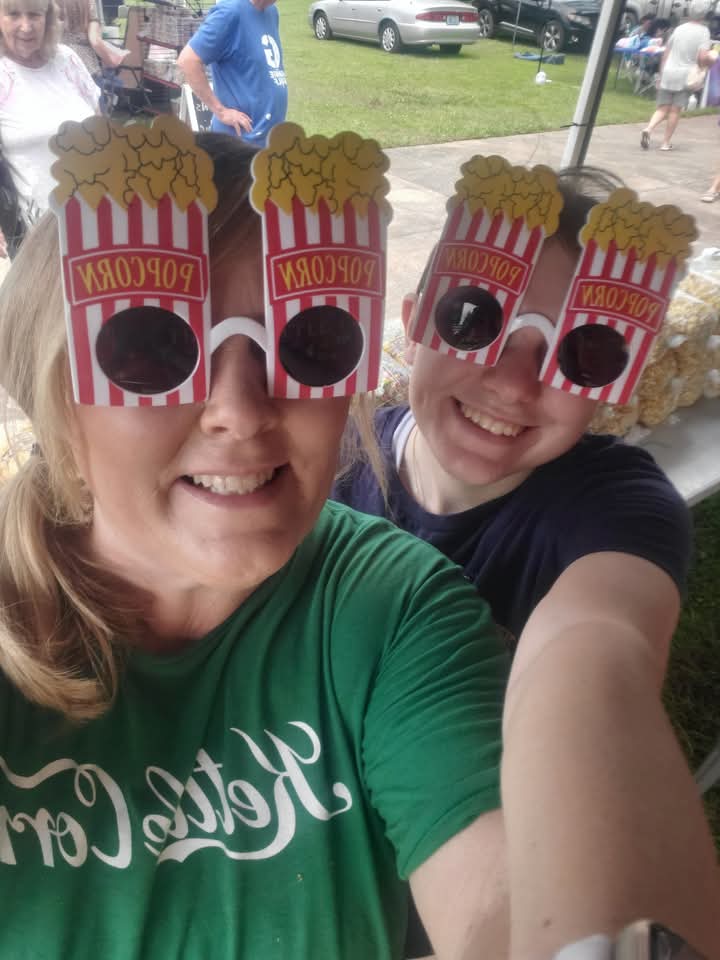 The Kettle Corn Poppers team smiling in popcorn glasses at an event.